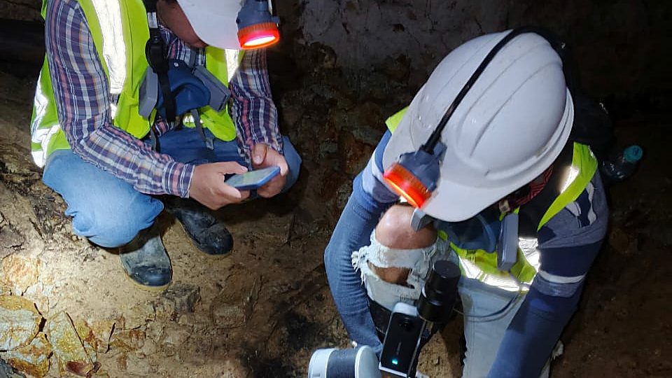 Dos profesionales con casco y chaleco reflectivo trabajando sobre una excavación de exploración