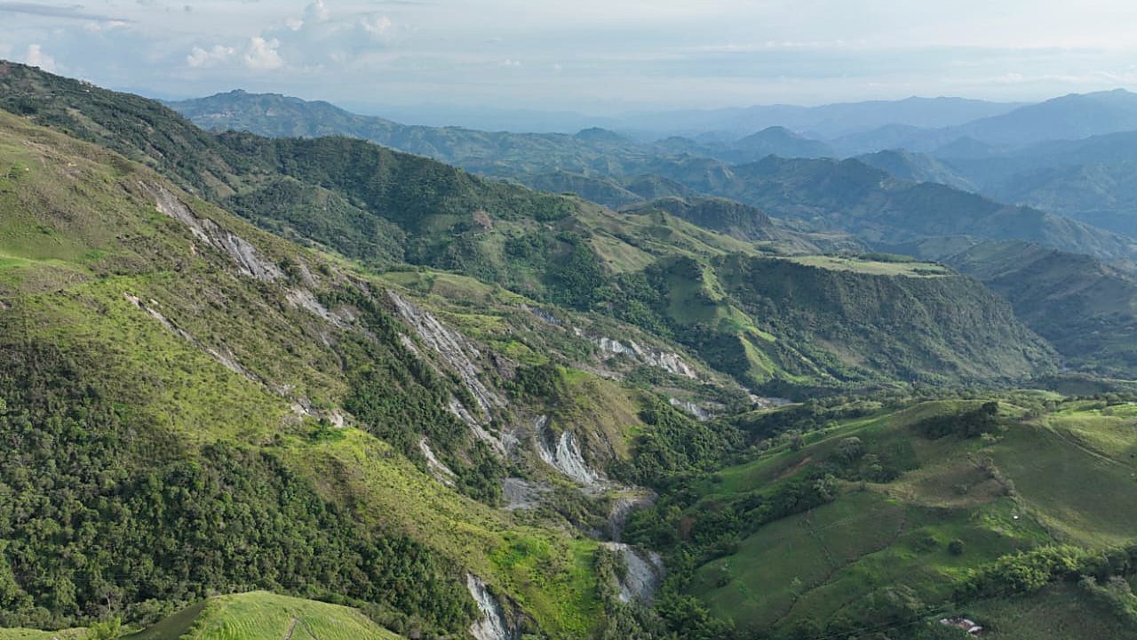 Vista aérea de una ladera con un movimiento en masa activo, con cultivos y vivienda dispersa en la parte baja