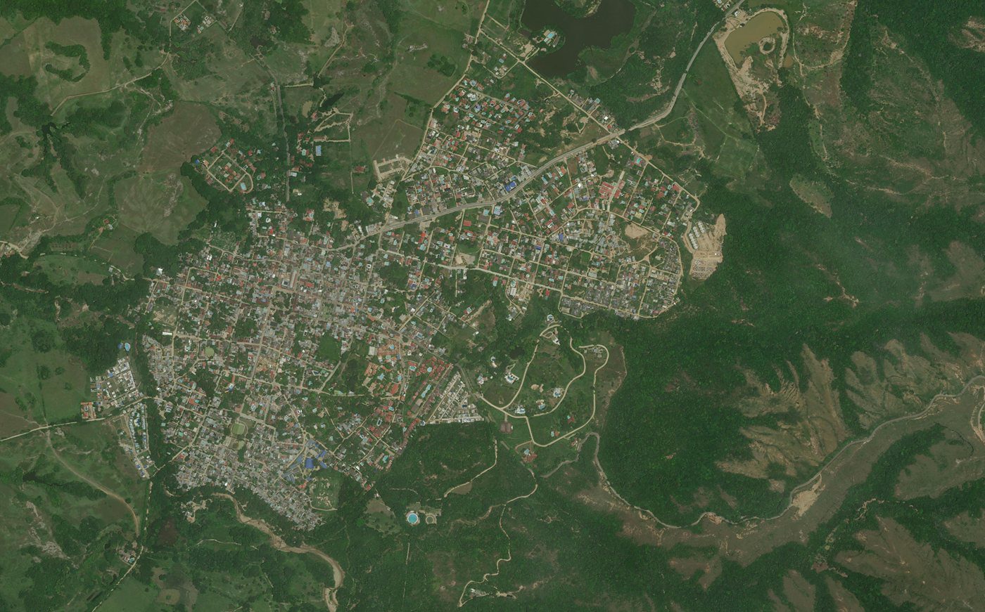 Imagen satelital de alta resolución de un casco urbano y su borde, con el tejido consolidado, los desarrollos dispersos y las vías de acceso