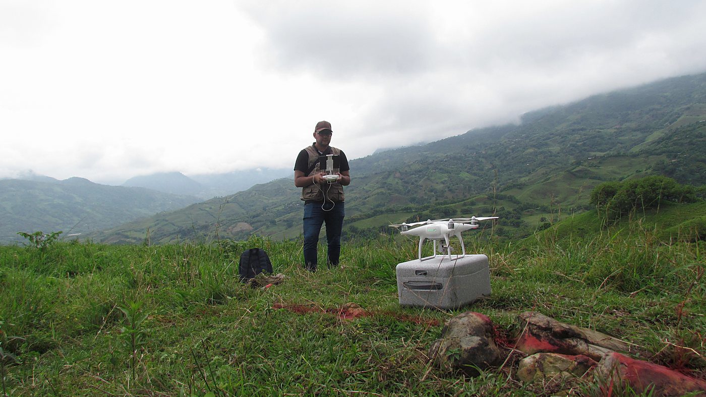 Operador de aeronave no tripulada con su control y el equipo dispuesto en una loma, con la cordillera al fondo